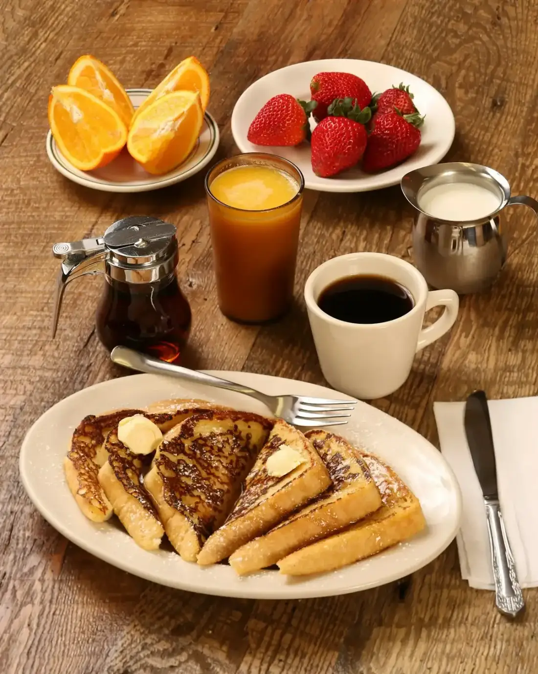 Mesa de café da manhã com rabanada, suco de laranja, café e morangos