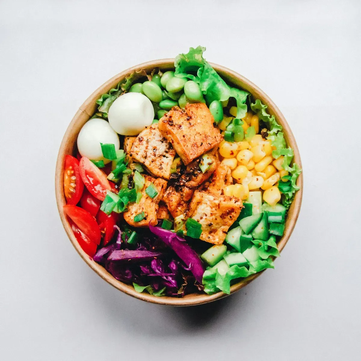 Tigela de salada com salmão em cubos, ovo, milho, pepino e repolho roxo