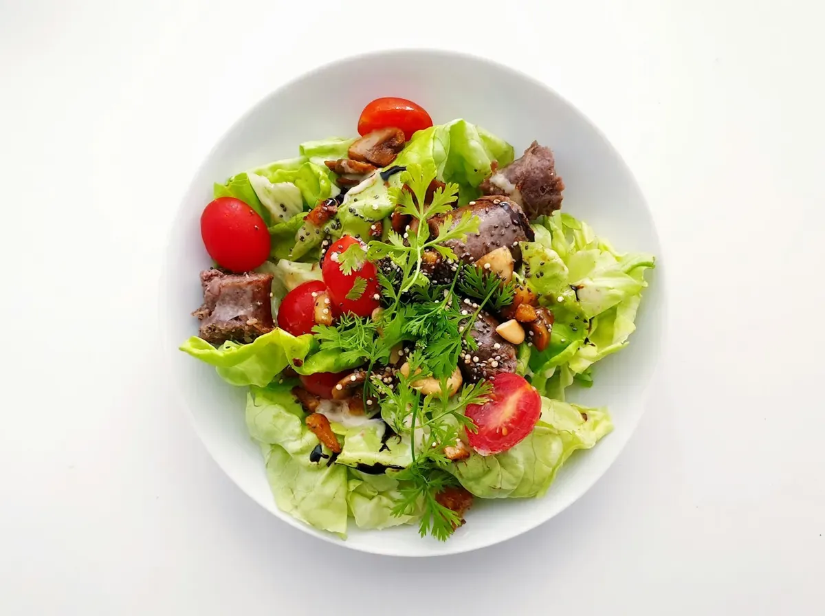 Salada de folhas com tomate-cereja em prato branco, vista de cima