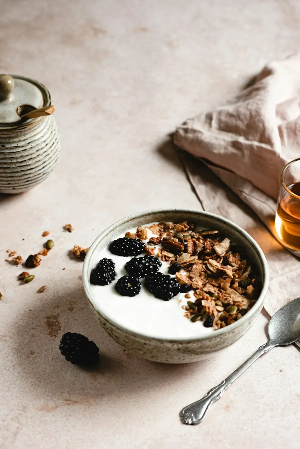 Tigela de iogurte com amora e granola sobre bancada